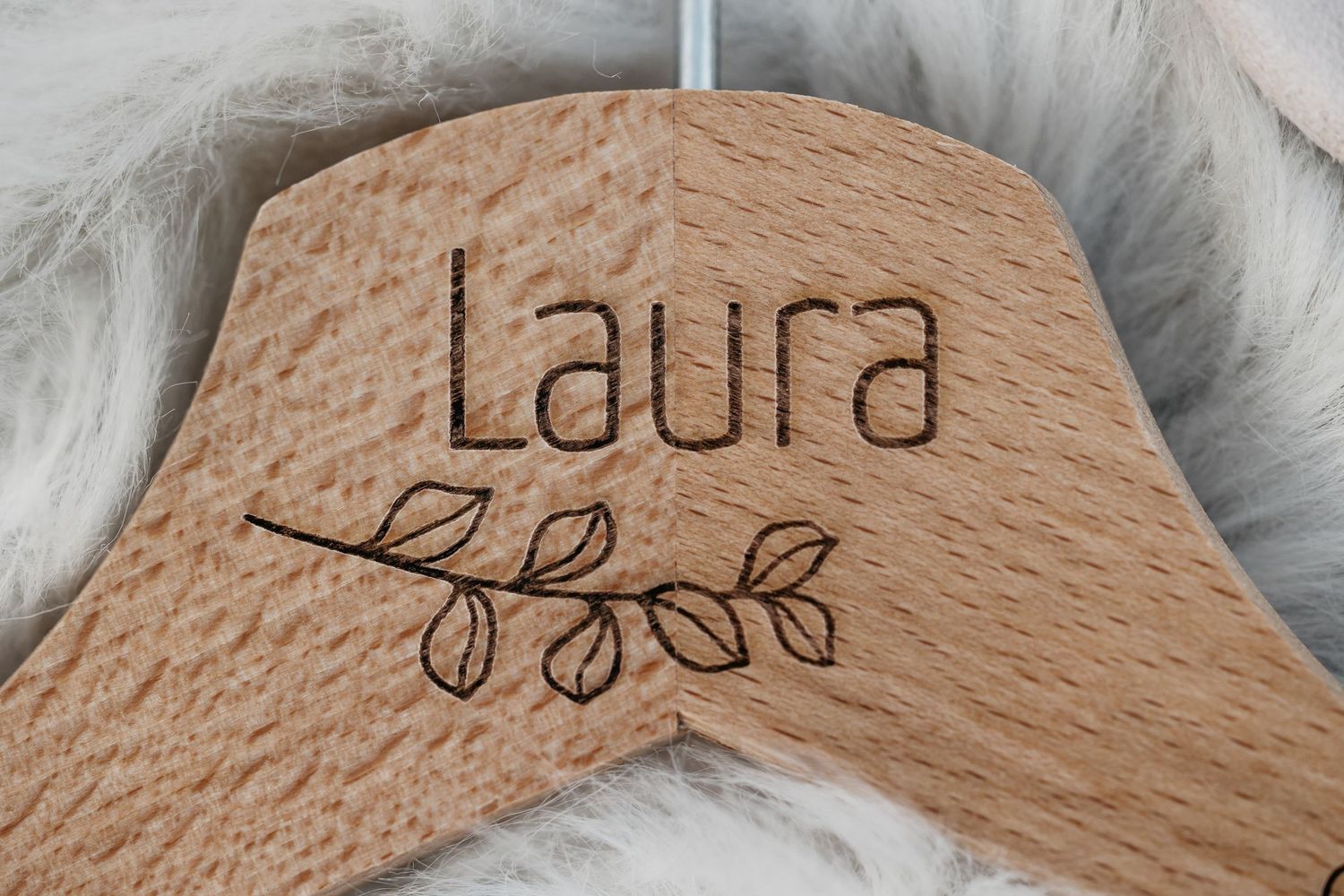Personalized wooden wedding dress hanger engraved with the name Laura and leaf design.