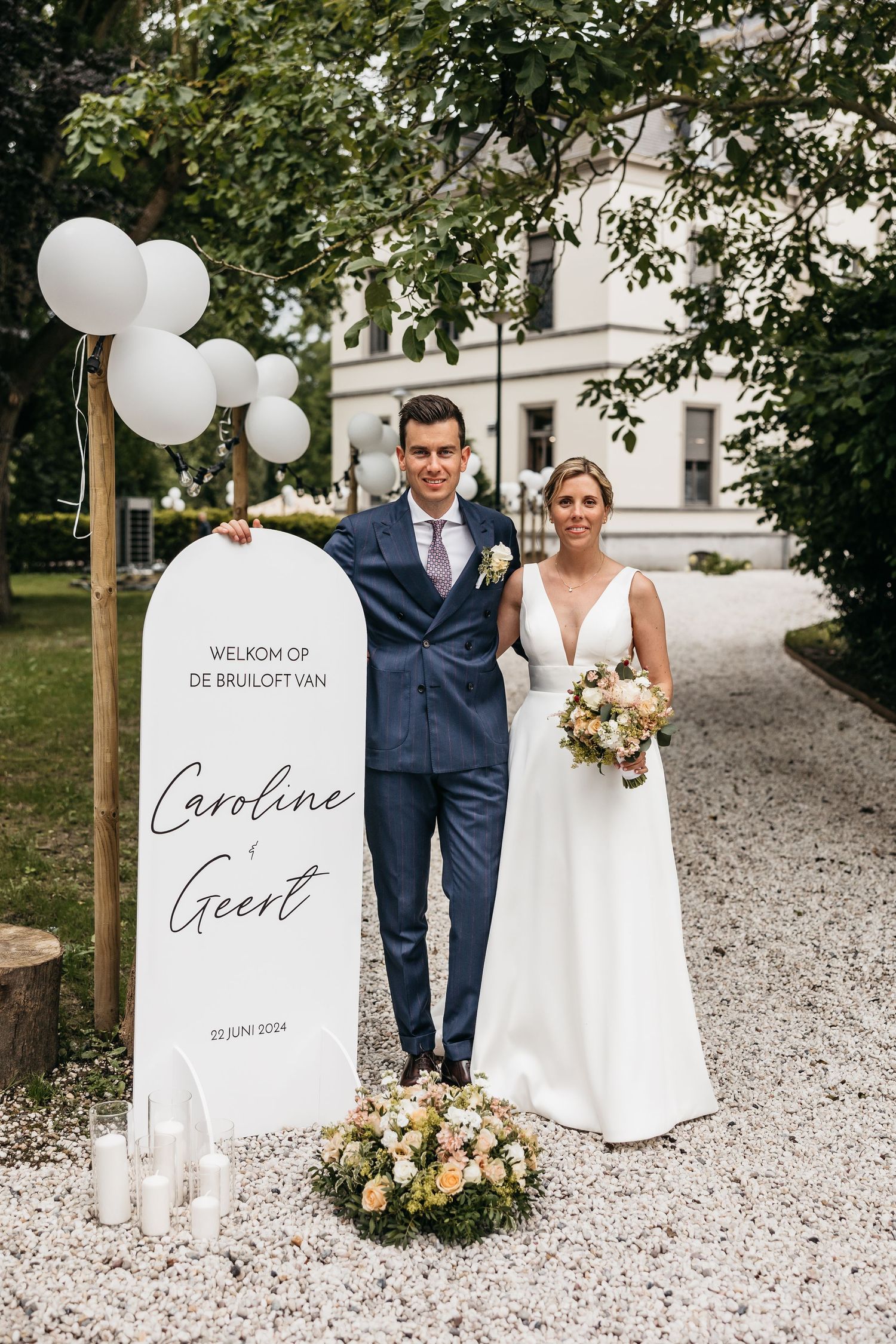 Bride and groom posing beside elegant wedding welcome sign for Caroline and Geert, June 2024.