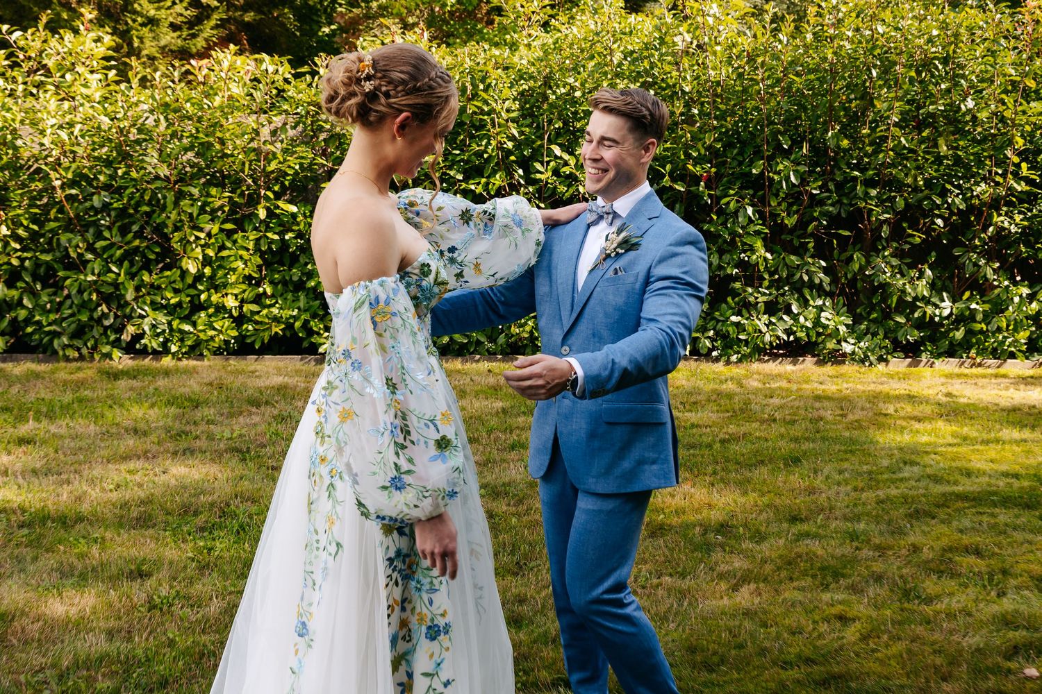 Bride and groom sharing a joyful first look moment on green lawn.