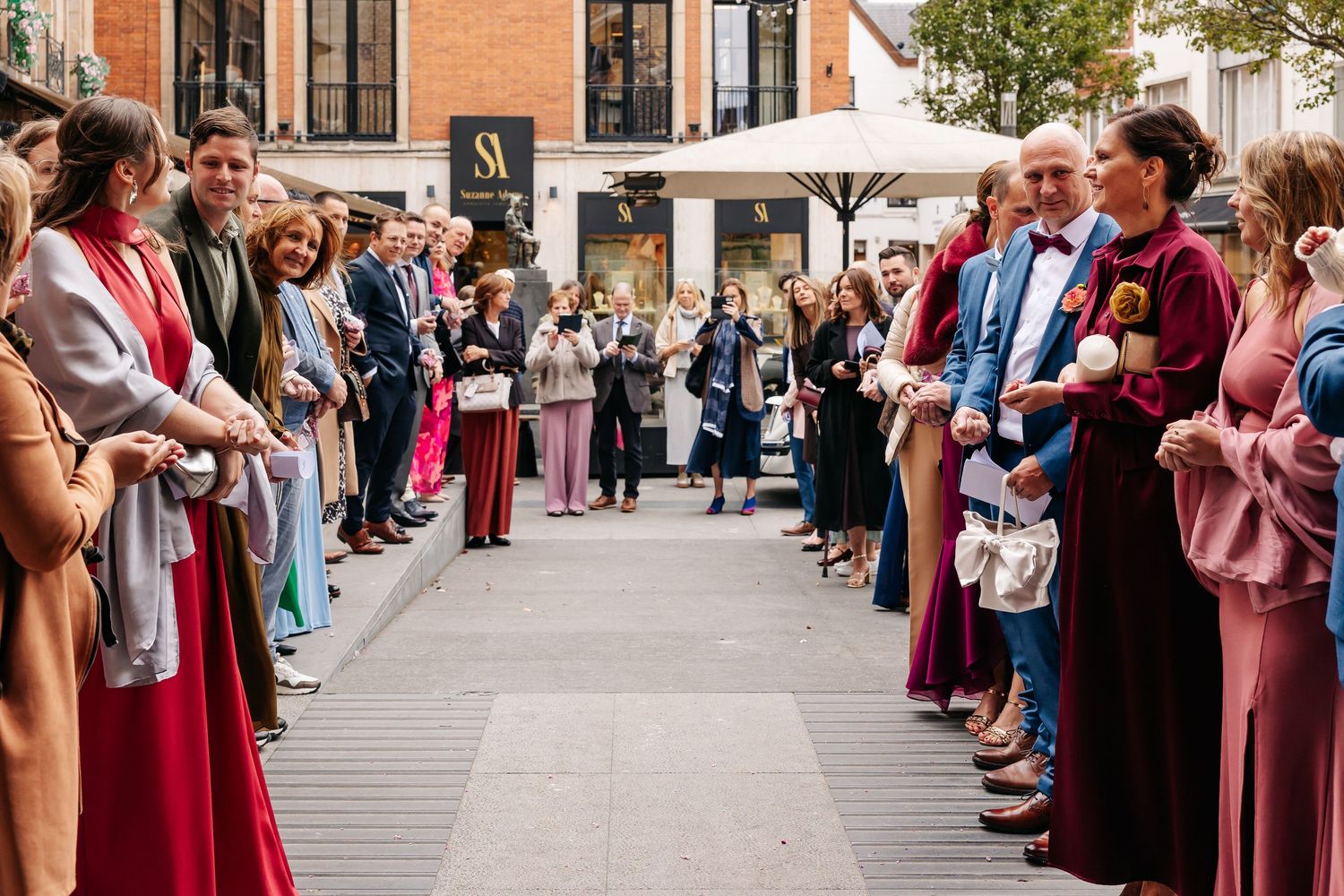 Wedding guests line up outside church forming a celebratory aisle for the newlyweds.