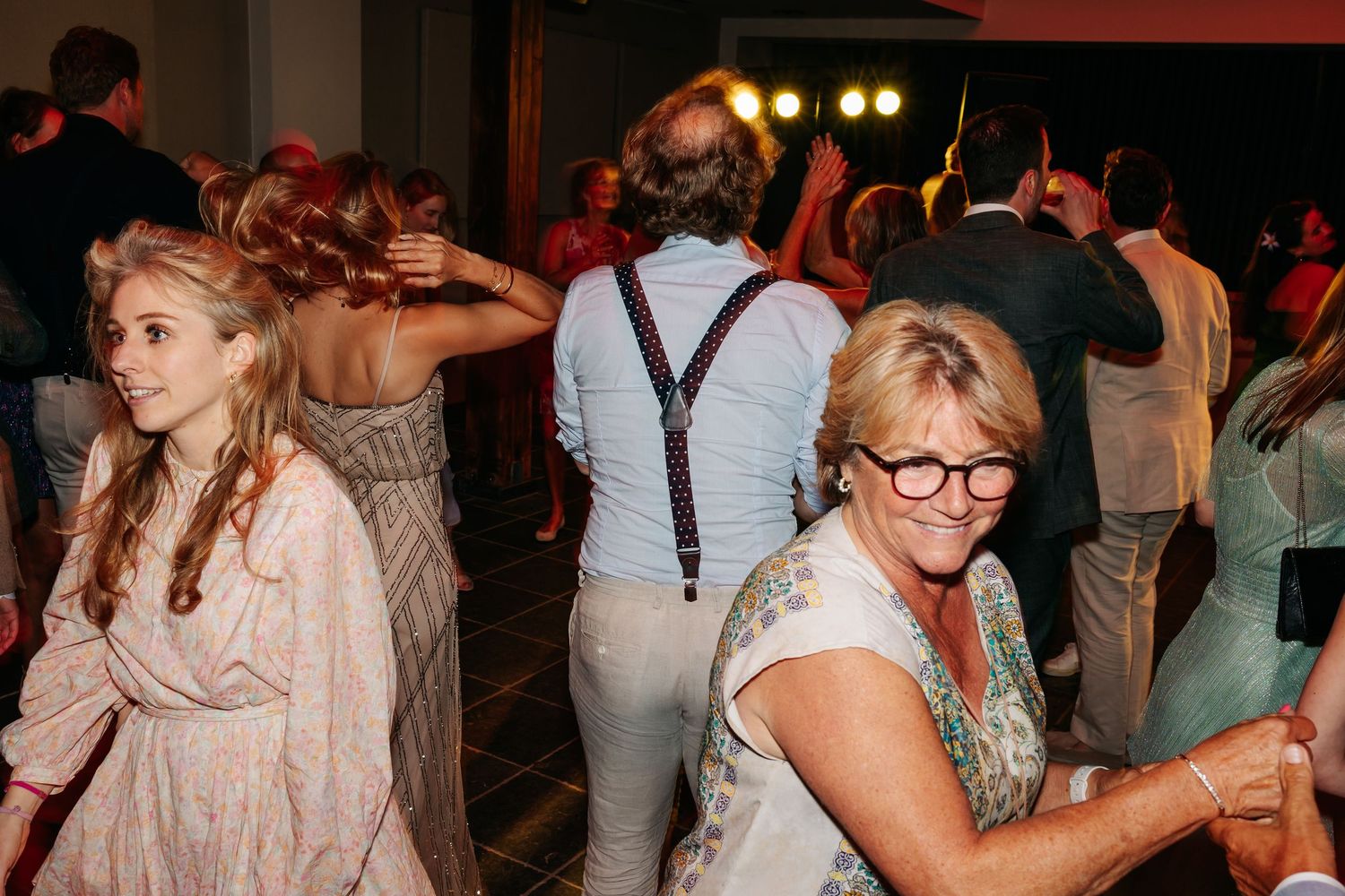 Guests dancing joyfully on crowded dance floor at lively wedding reception party.