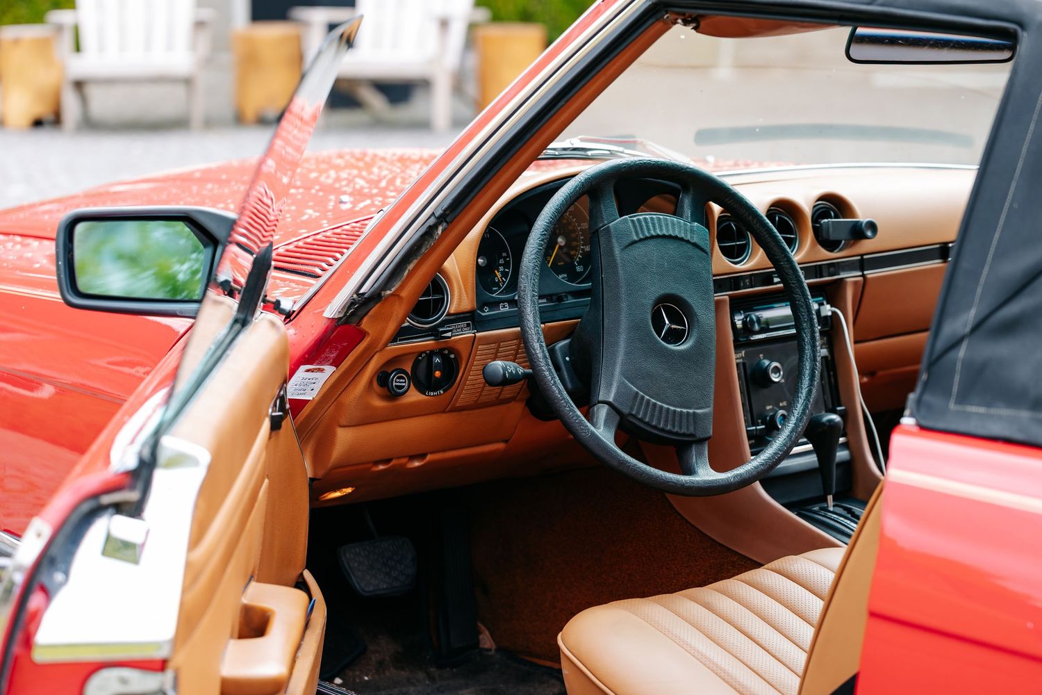 Interior view of a classic red Mercedes-Benz convertible with tan leather seats and wood-trimmed steering wheel.