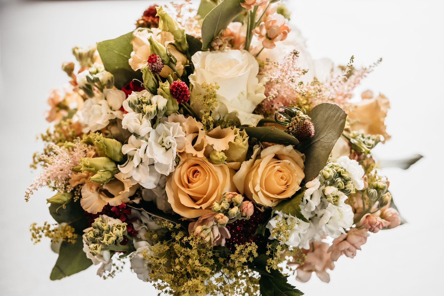 Elegant wedding bouquet featuring peach roses, white flowers, and greenery arranged beautifully.