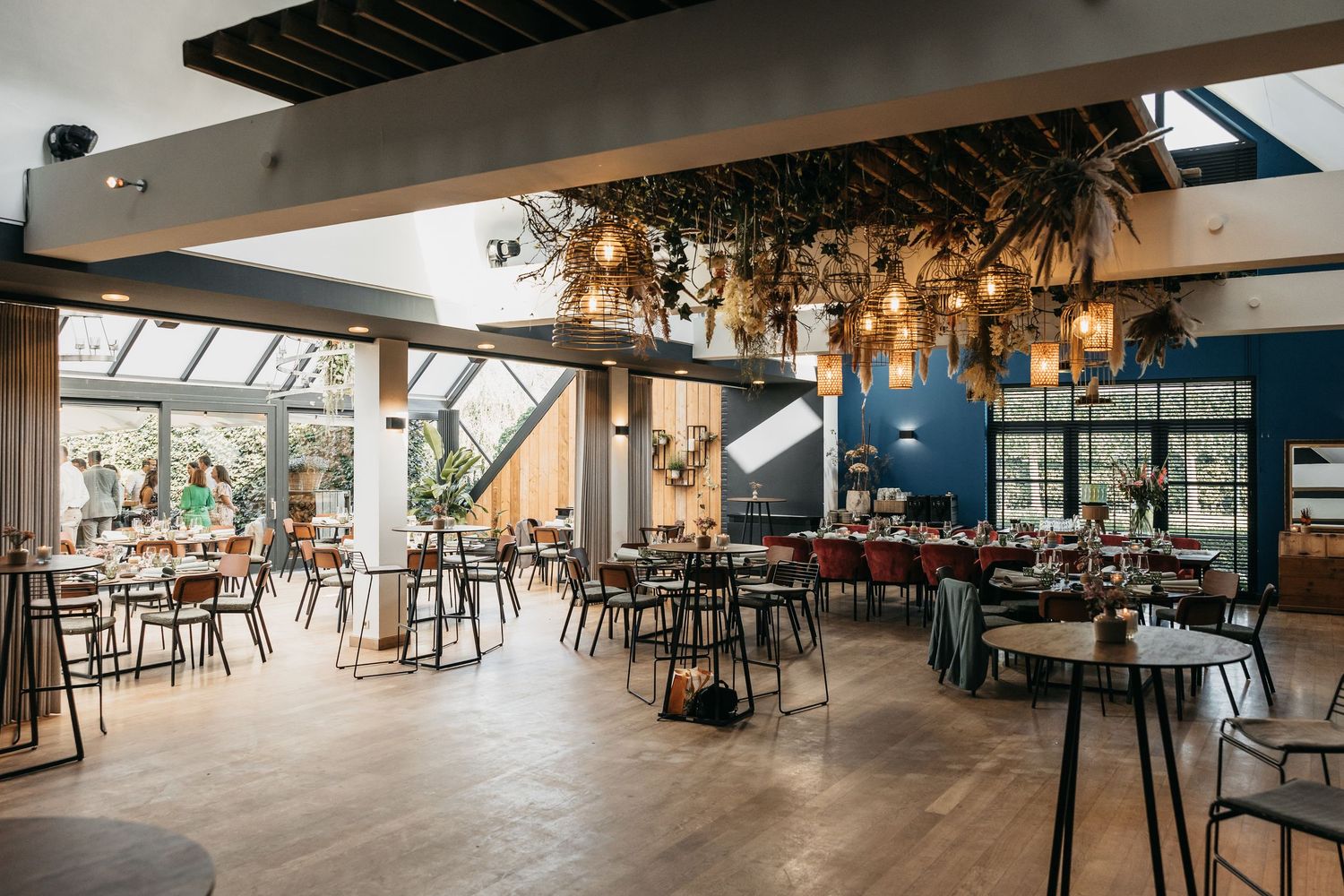 Modern industrial wedding venue with open-plan dining area, hanging Edison lights, and a glass conservatory extension.