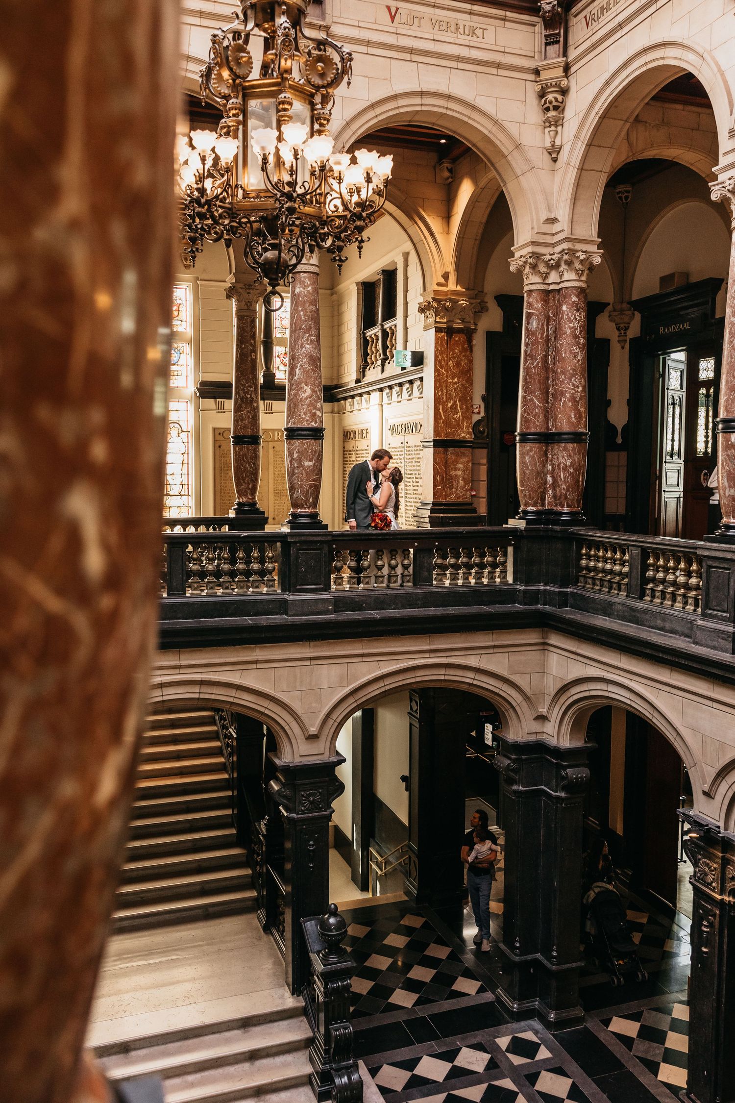 Wedding couple embracing on balcony in stunning historic building interior.