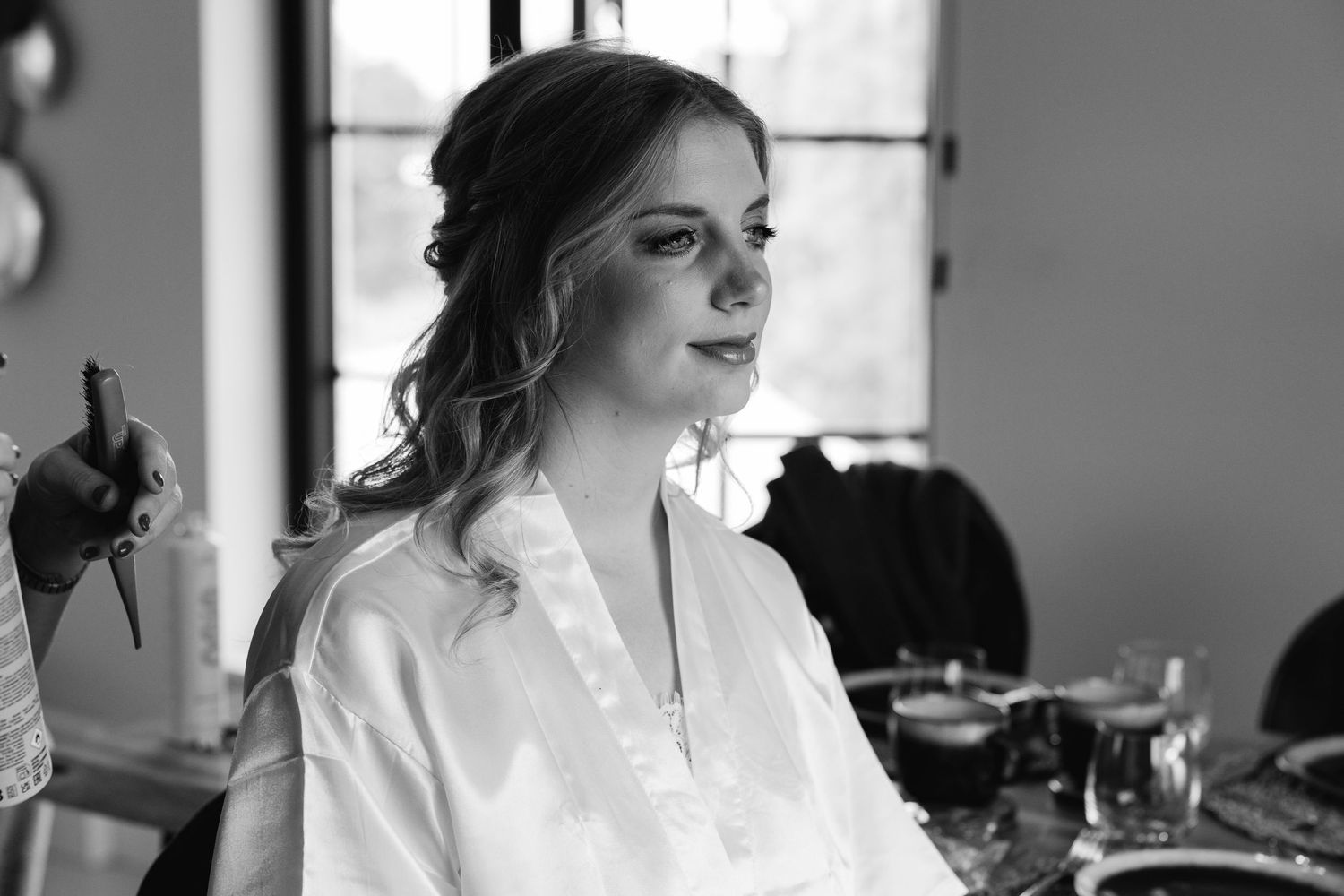 Black and white portrait of bride in white robe during wedding morning hair and makeup session.