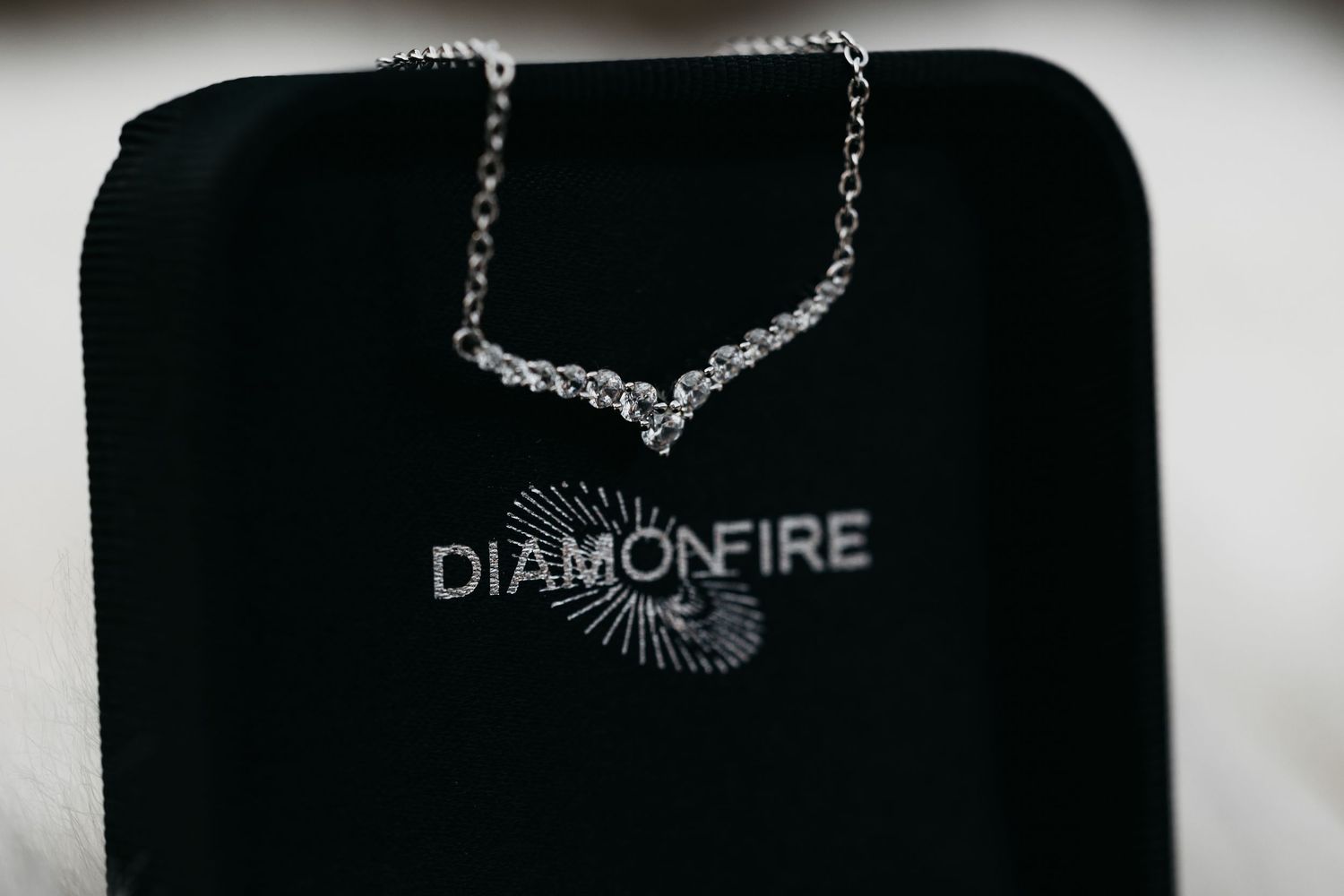 Diamond V-shaped pendant necklace displayed on a black Diamonfire jewelry pouch.