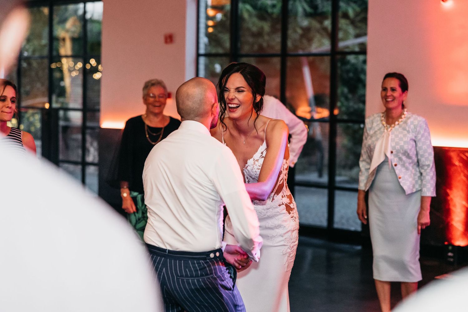 Bride laughing joyfully while dancing with a guest at her elegant wedding reception.