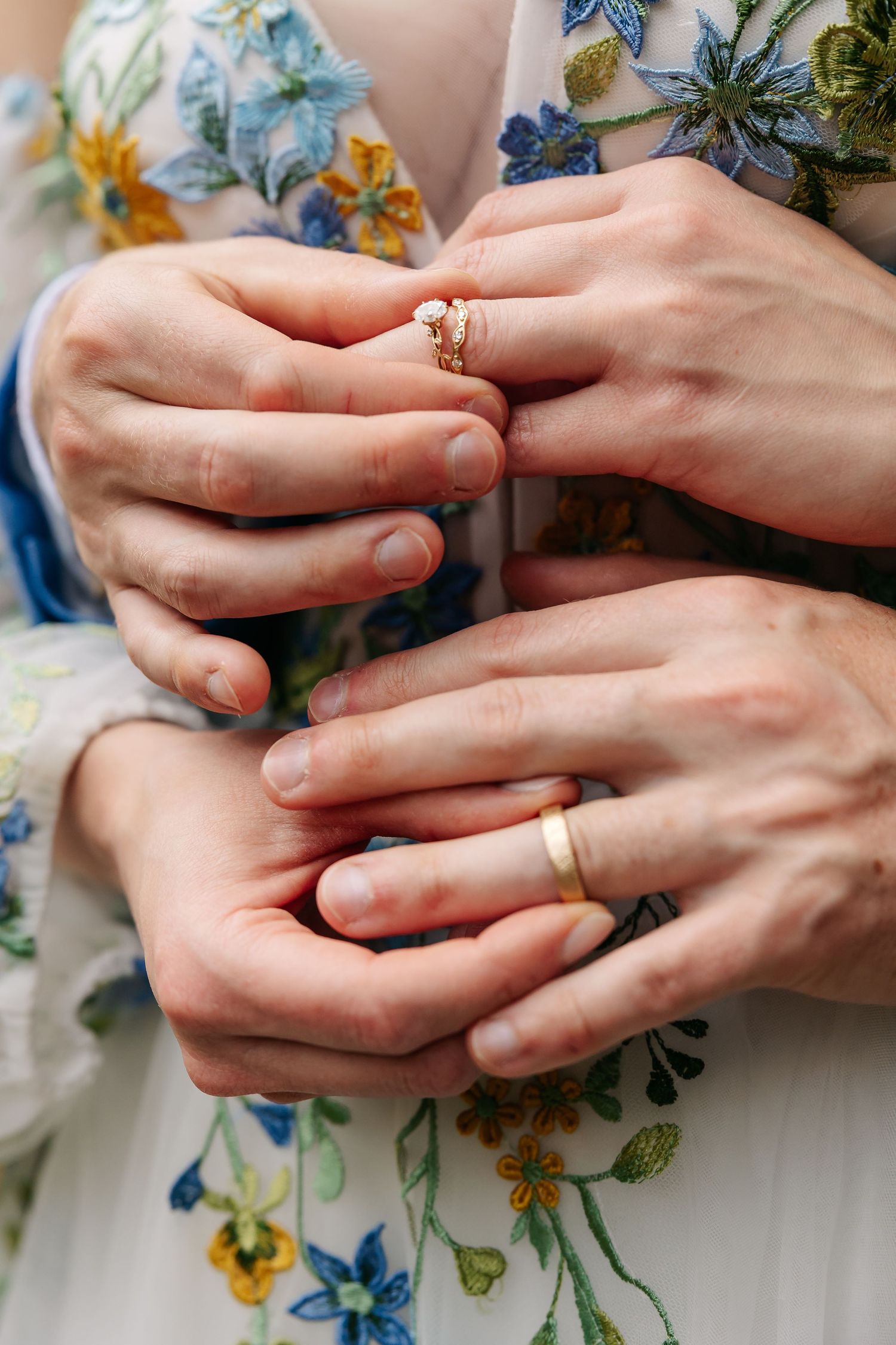 Close-up of newlyweds hands showing gold wedding bands and diamond engagement ring.