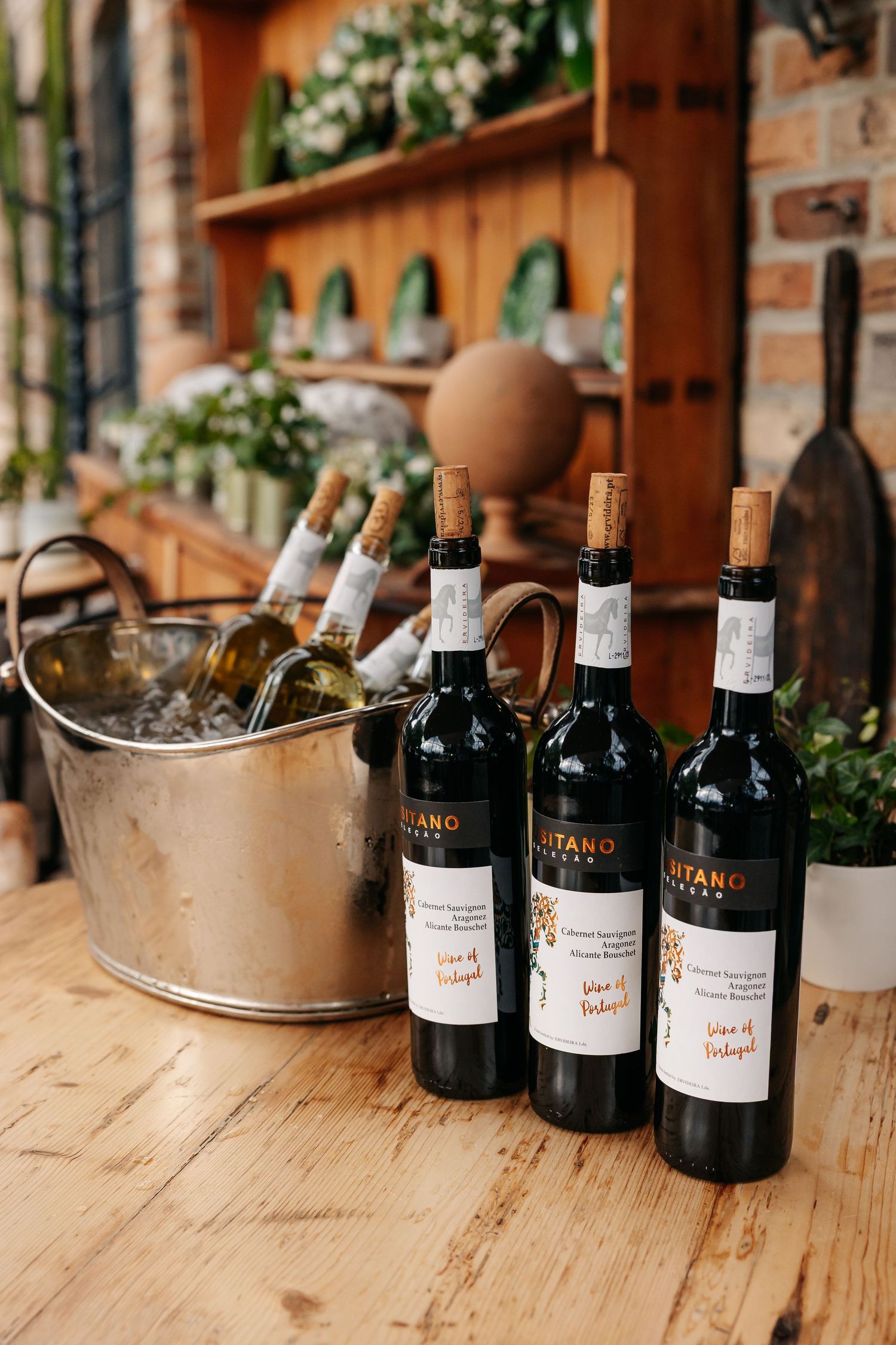 Three red wine bottles labeled Vina de Portugal displayed on rustic wooden table.