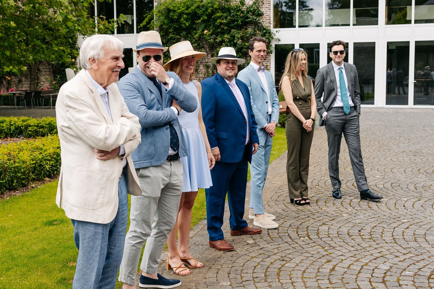 Group of elegantly dressed guests posing outdoors at a summer wedding event.