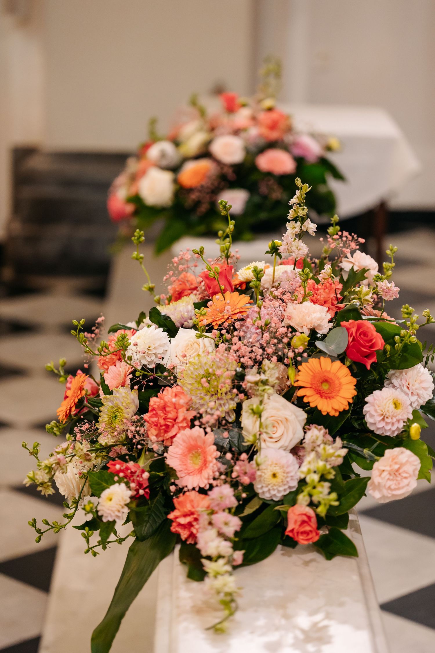 Colorful wedding floral arrangement featuring coral roses, gerberas, and mixed blooms.