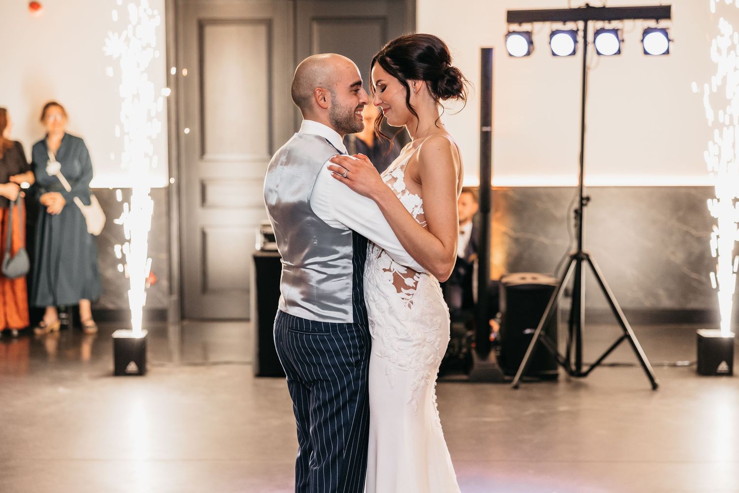 Bride and groom dancing closely during first dance with sparkling light effects in the background.