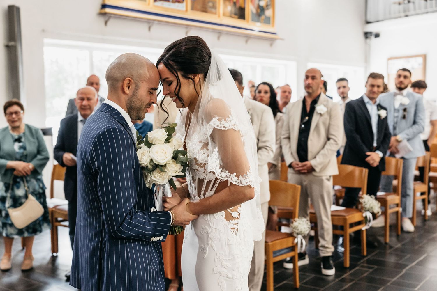 Bride and groom share intimate forehead touch moment at church altar.