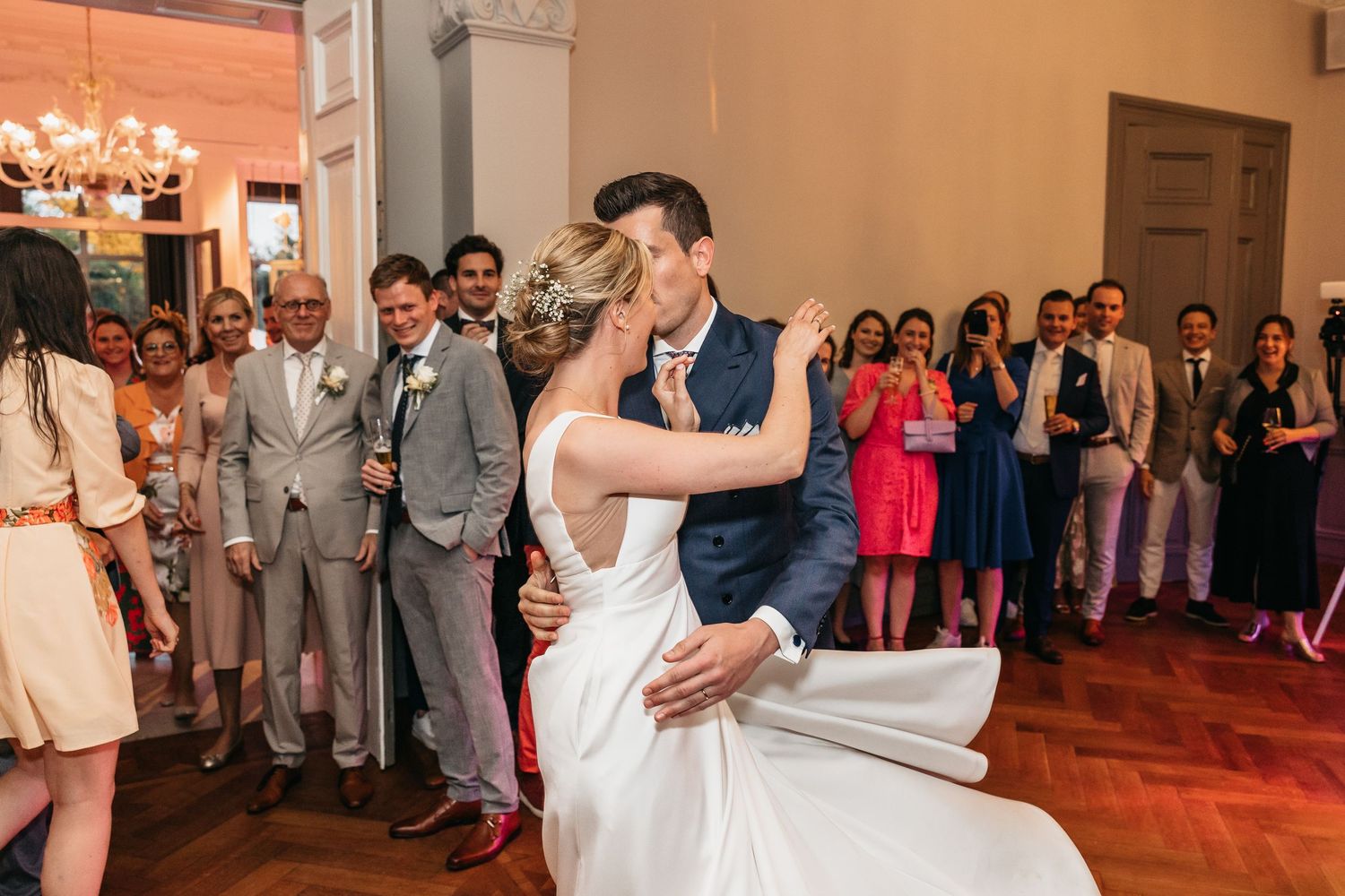 Newlyweds sharing a passionate kiss during their first dance at wedding reception.