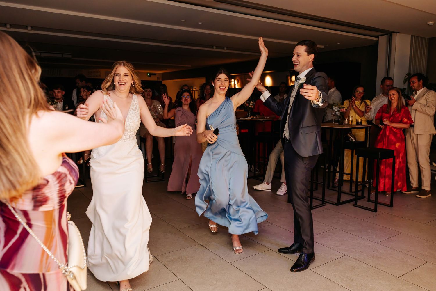 Bride, groom, and guests dance energetically on the floor at a lively wedding reception.