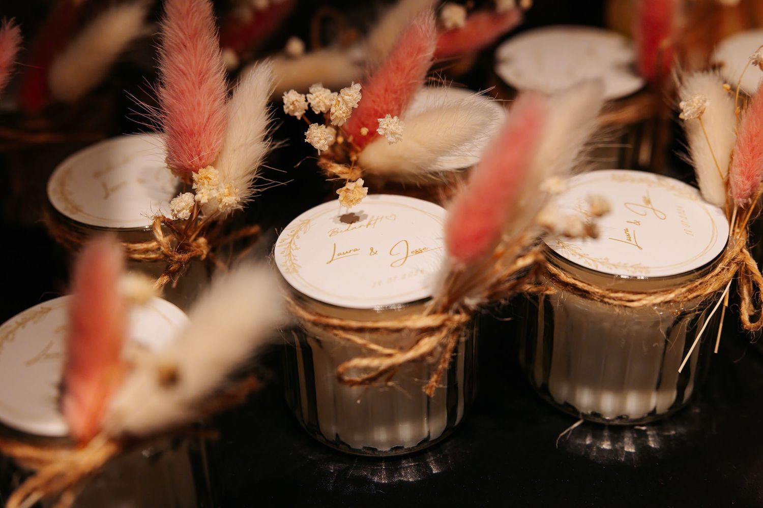 Personalized wedding favor candles decorated with dried pampas grass and twine.