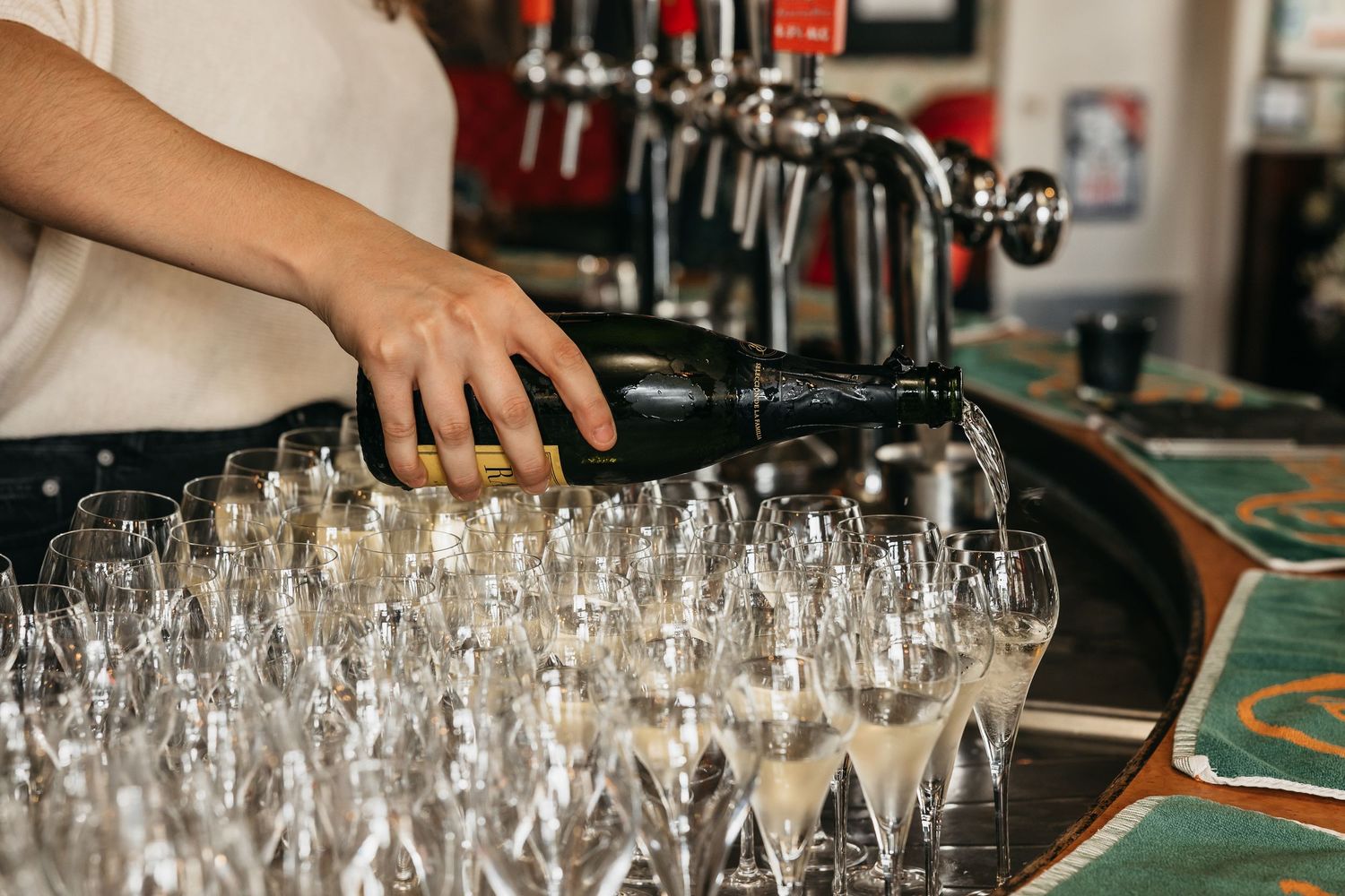 Bartender pouring champagne into elegant flute glasses arranged on round tray at wedding reception.