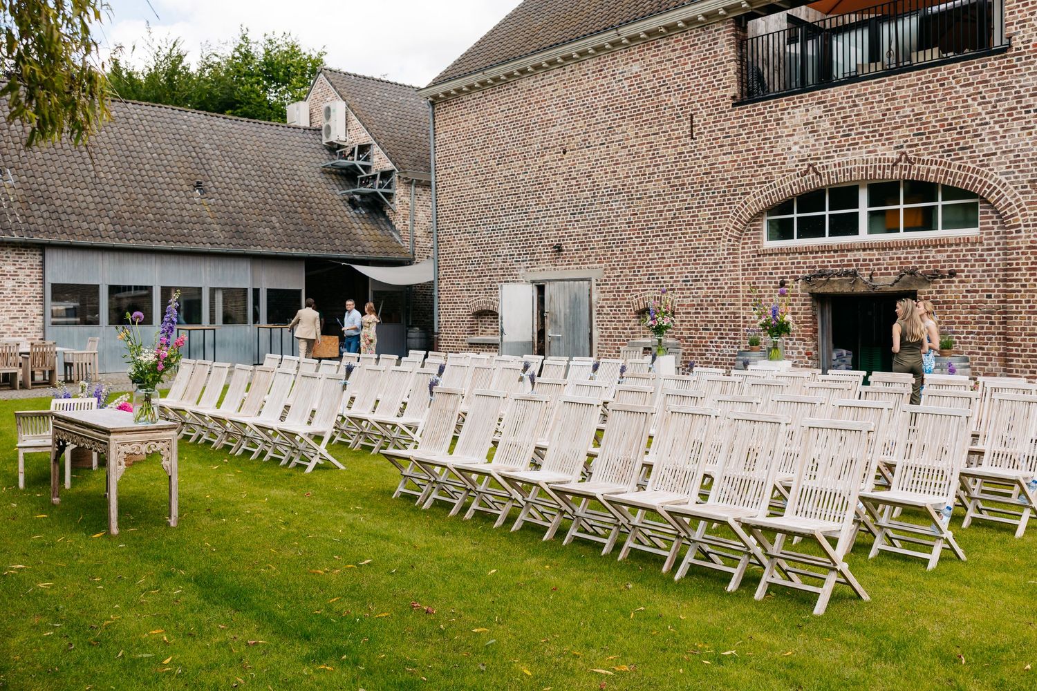 Rows of white wooden folding chairs set up on lawn for outdoor wedding ceremony.
