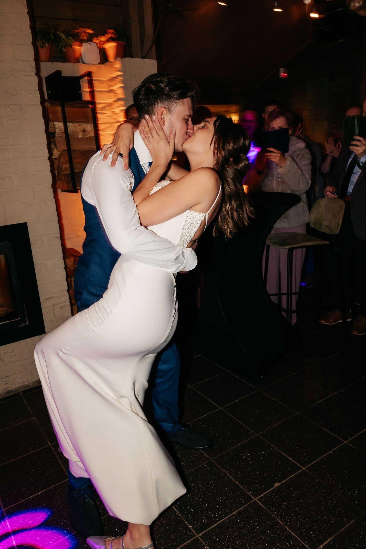 Newlyweds sharing a passionate kiss on the dance floor during their wedding reception.