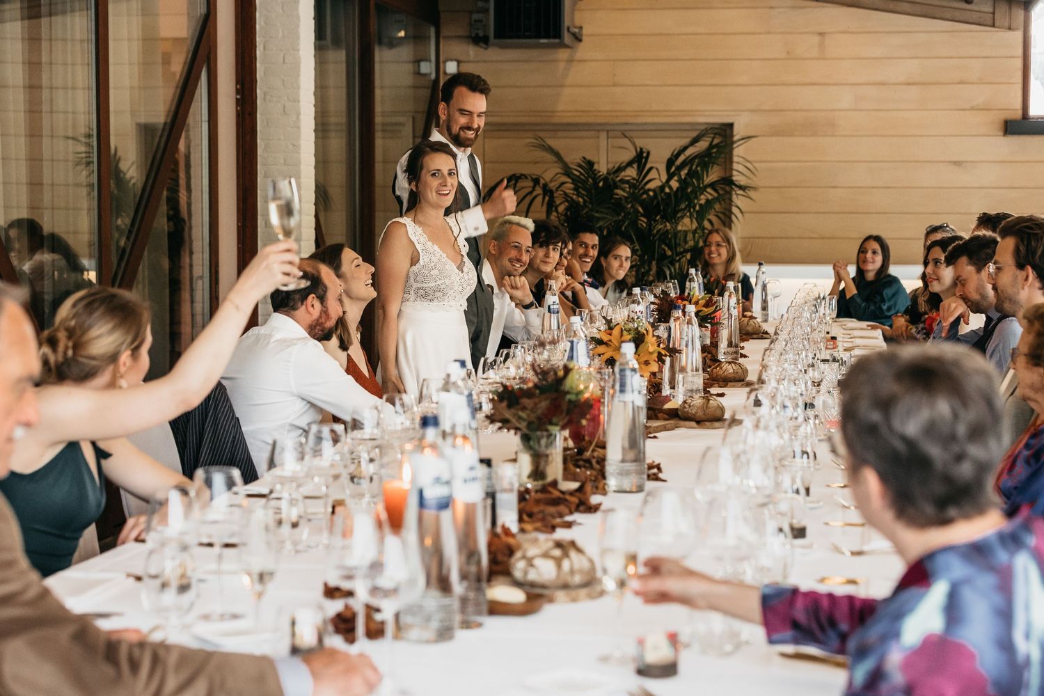 Wedding couple toasting with guests at a long elegantly set reception dinner table.