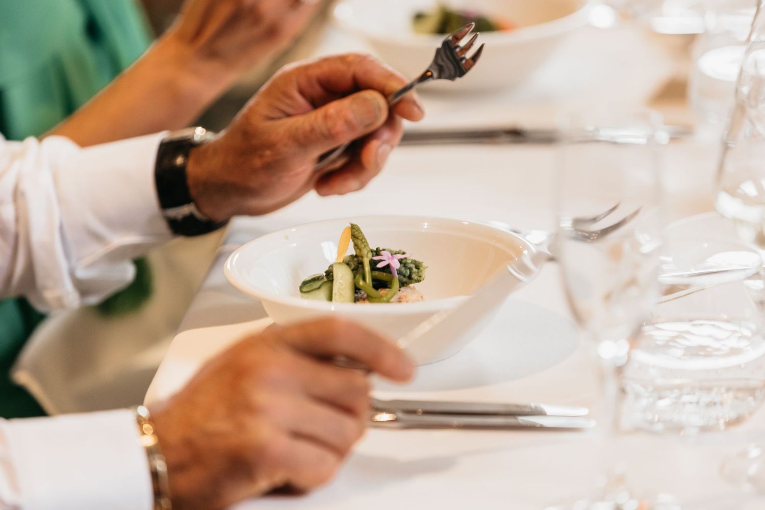 Wedding guest enjoys elegantly plated gourmet appetizer with vegetables at a fine dining reception table.