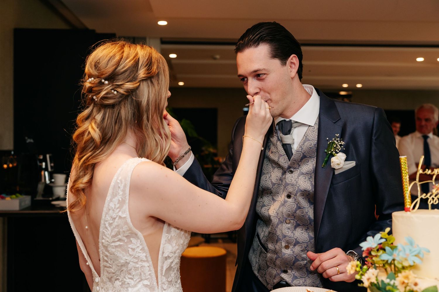 Bride feeds groom a piece of wedding cake during wedding reception celebration.