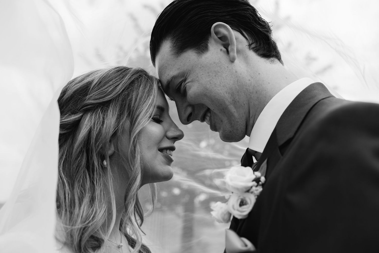 Black and white close-up of bride and groom sharing a tender forehead-to-forehead romantic moment.