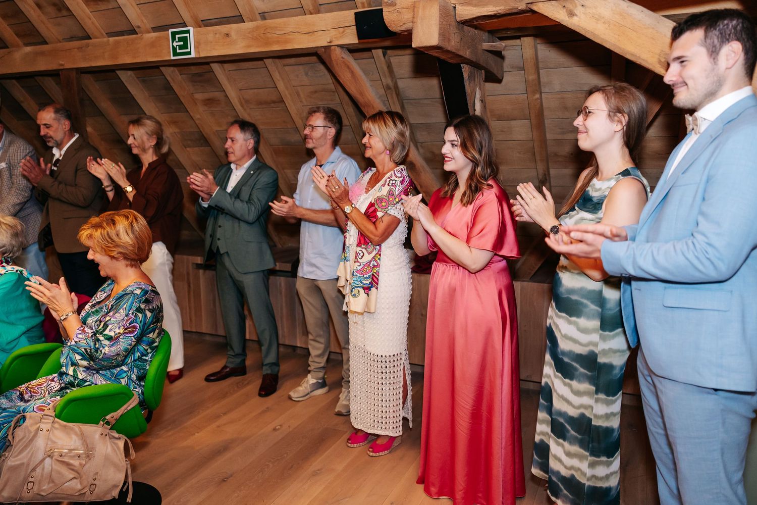 Wedding guests applauding and celebrating in a rustic attic venue reception hall.