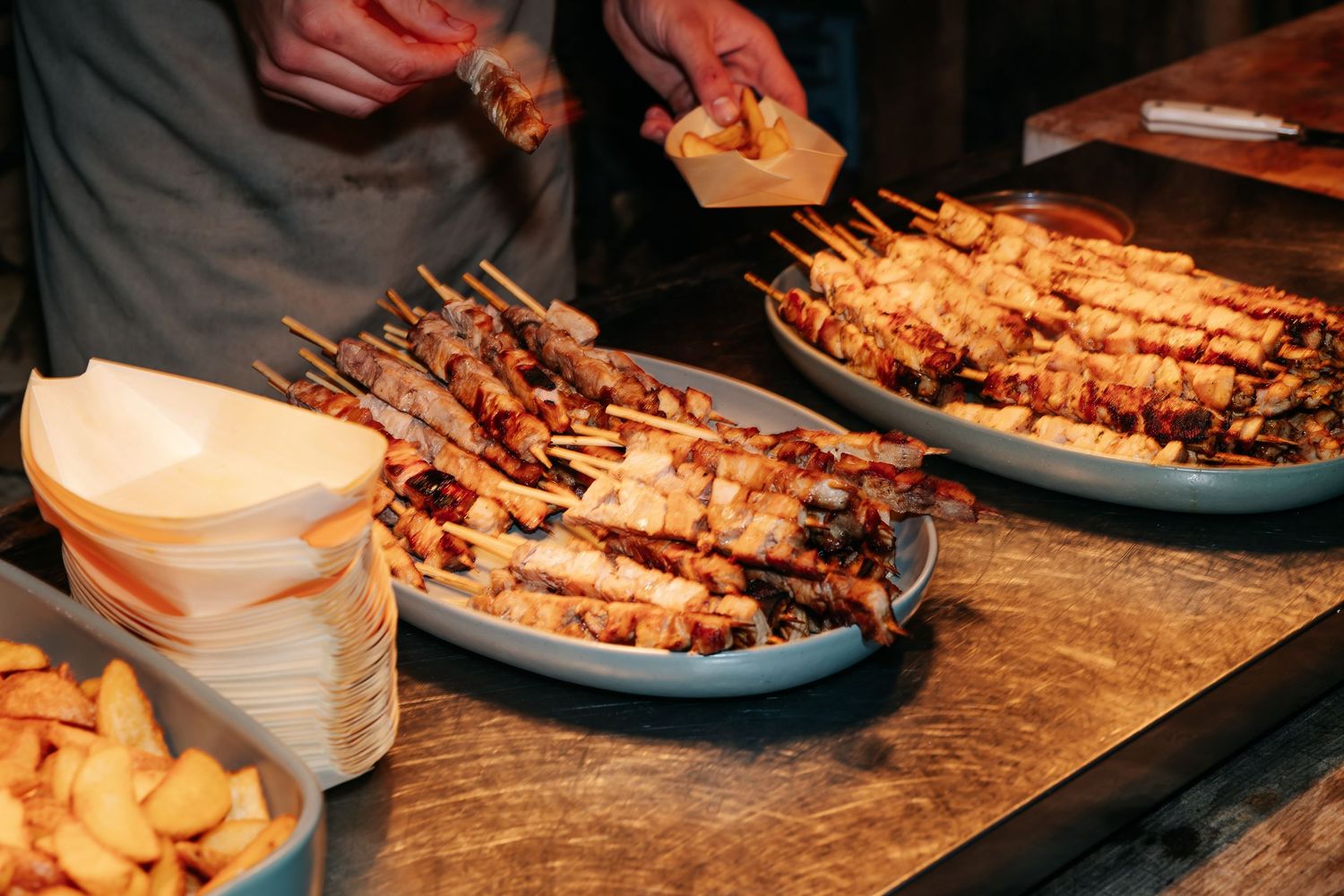 Grilled meat skewers and fries served on plates at a wedding catering food station.