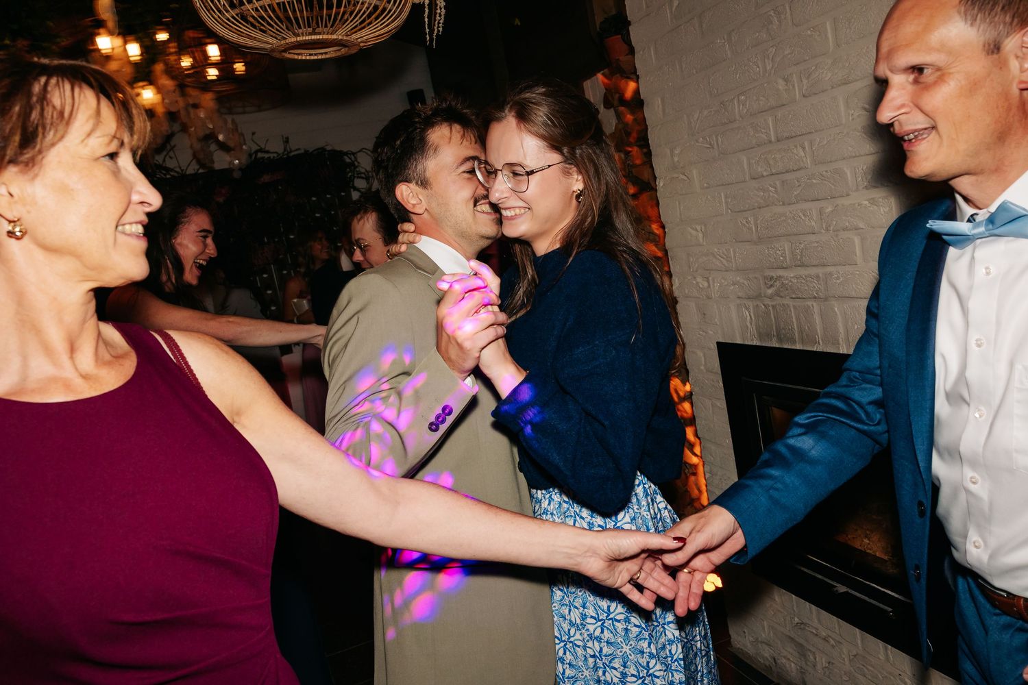 Wedding guests joyfully dancing and holding hands together on the reception dance floor.