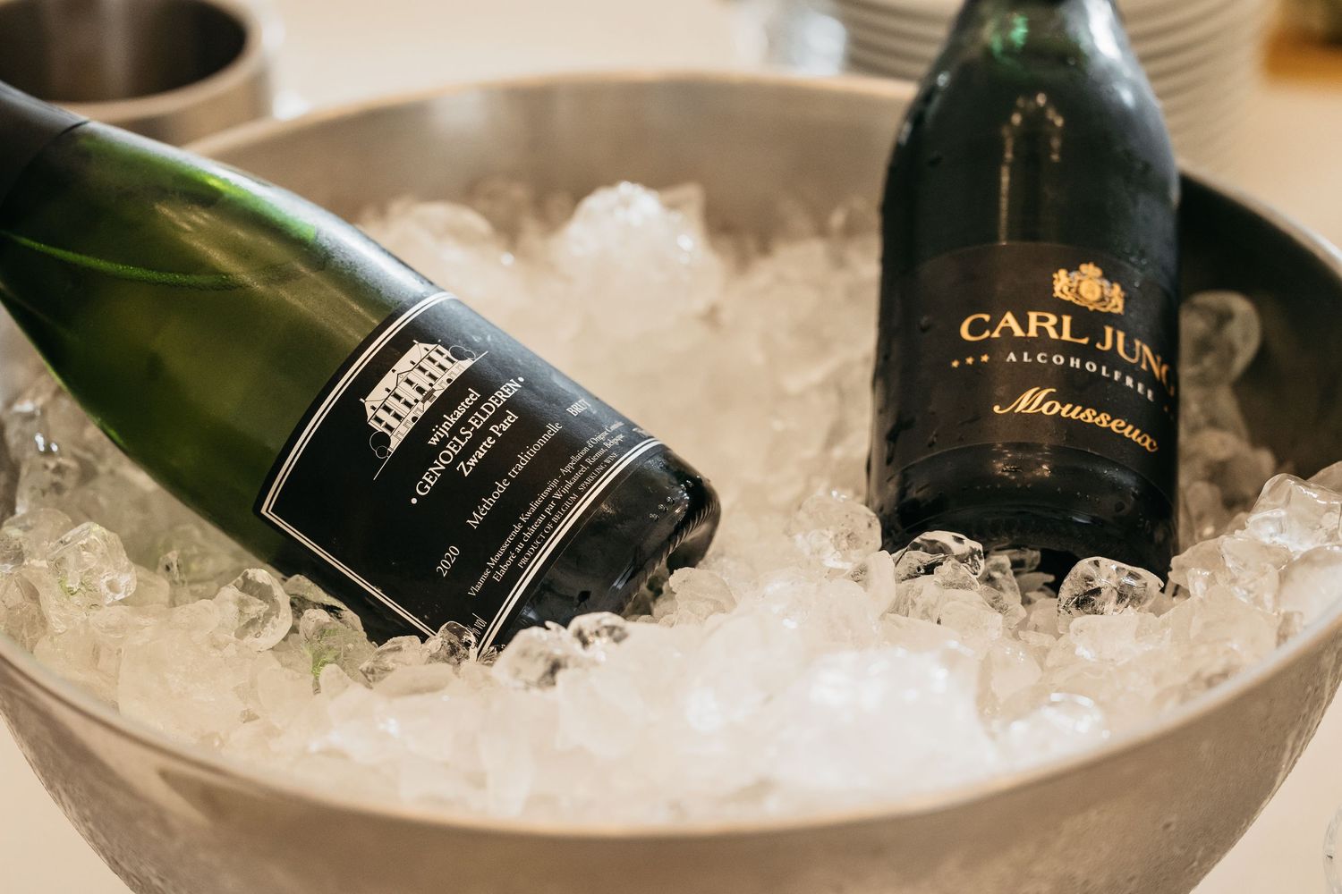 Two champagne bottles chilling in ice bucket at wedding reception celebration.