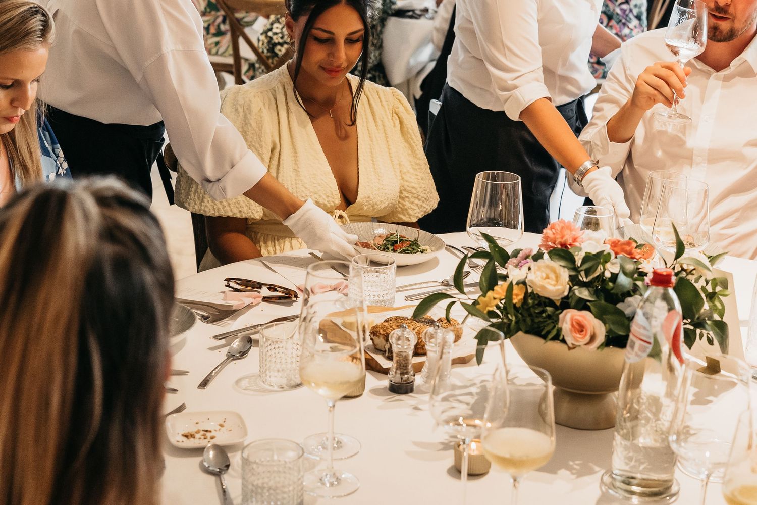 Wedding guest being served a plate of food at an elegant reception dinner table.