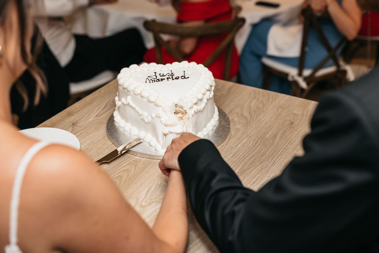 Bride and groom cutting white heart-shaped wedding cake together at their reception celebration.