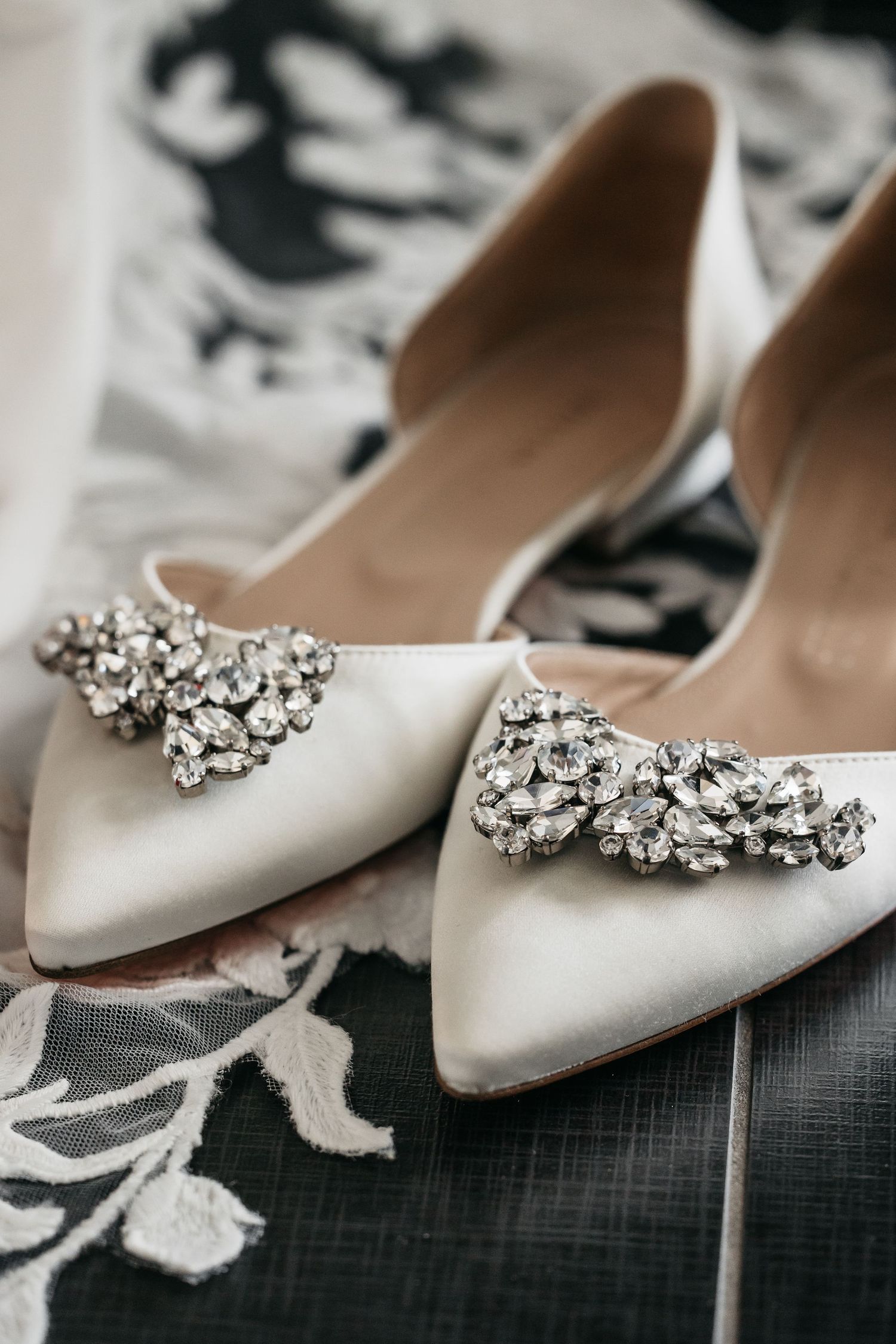Elegant white satin bridal heels with crystal jewel embellishments on pointed toe.