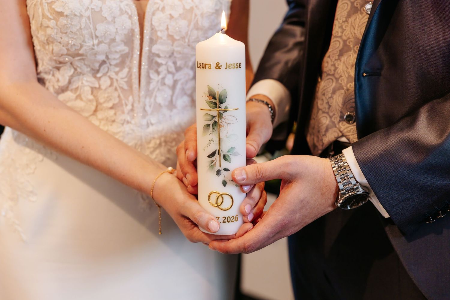 Bride and groom hold decorated unity candle together during church wedding ceremony.