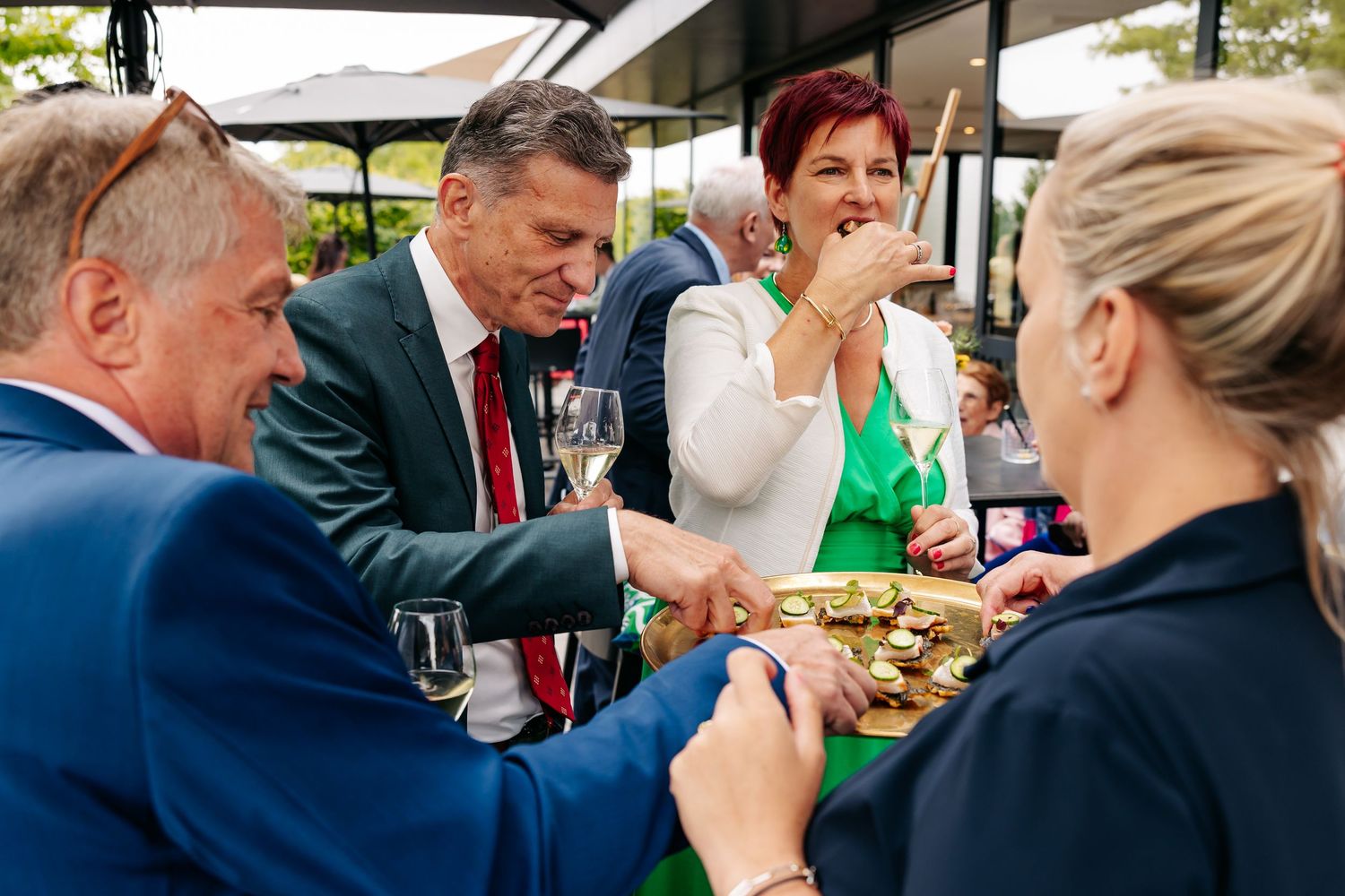 Wedding guests enjoying canapes and champagne at outdoor cocktail reception.
