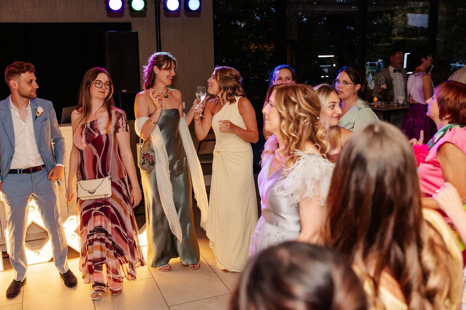 Wedding guests dancing and celebrating together on the dance floor at evening reception.