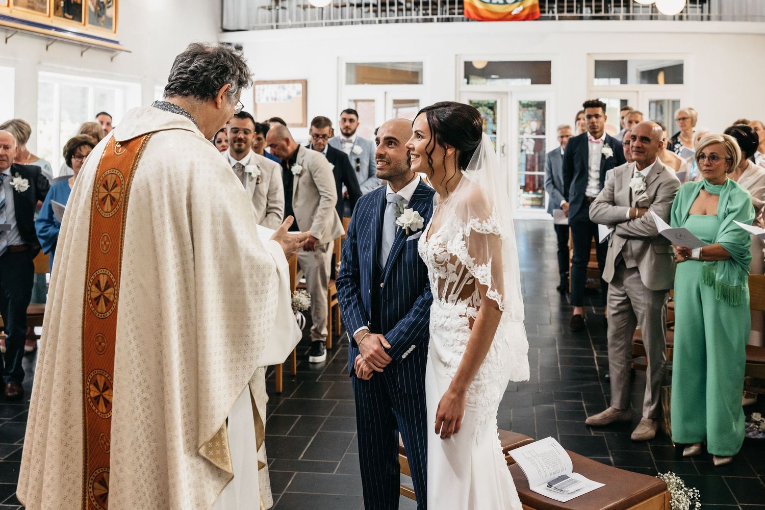 Bride and groom exchange vows before a priest during a church wedding ceremony.