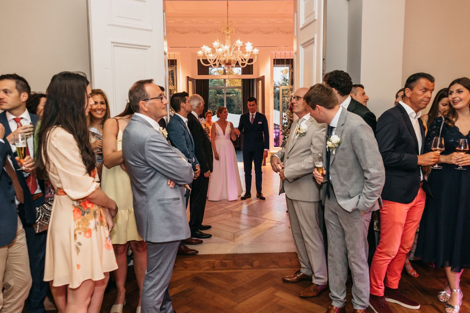 Wedding guests mingling and socializing in a grand chandelier-lit reception hall.