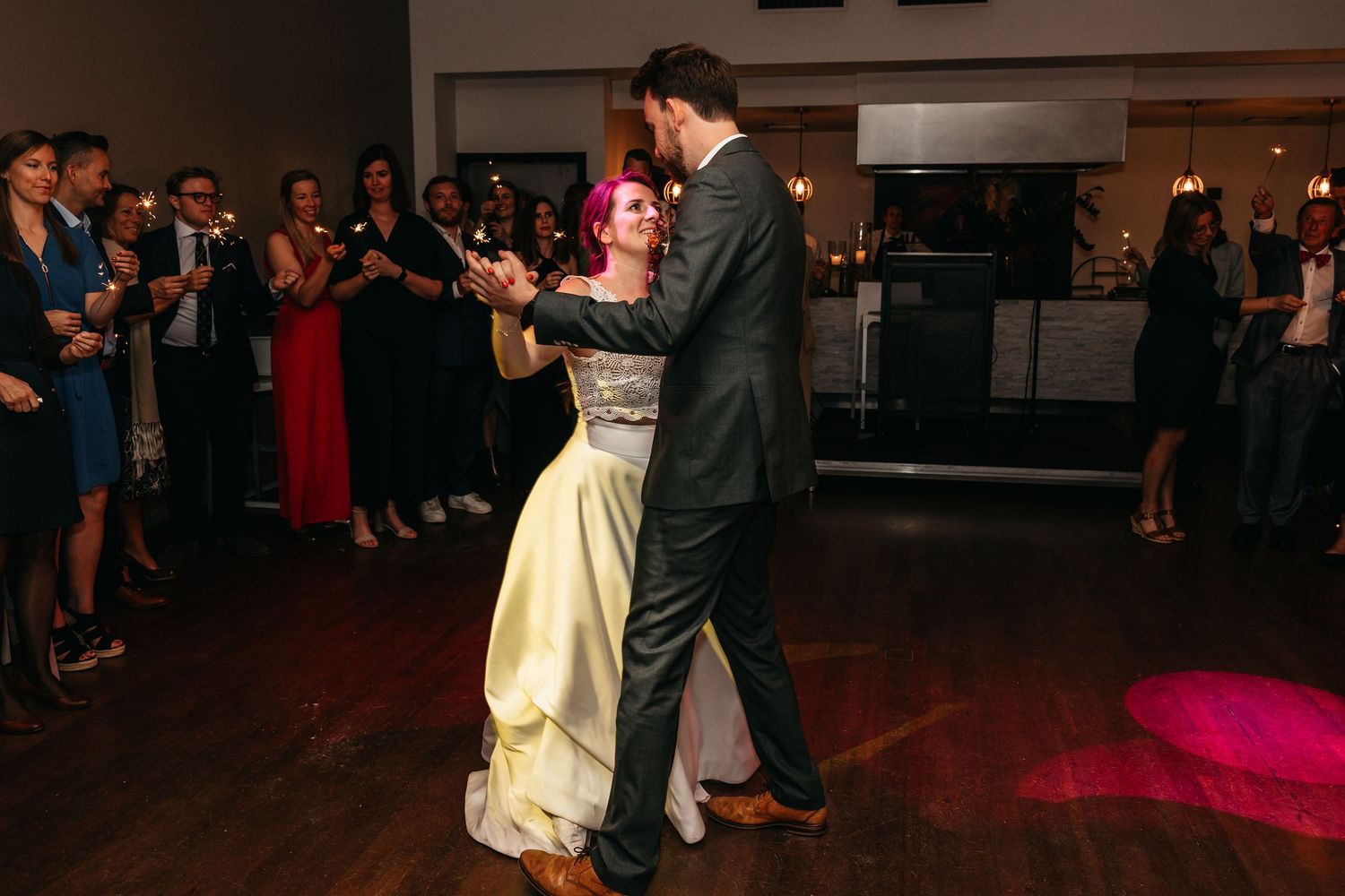 Couple dancing together on the wedding reception dance floor with guests watching.