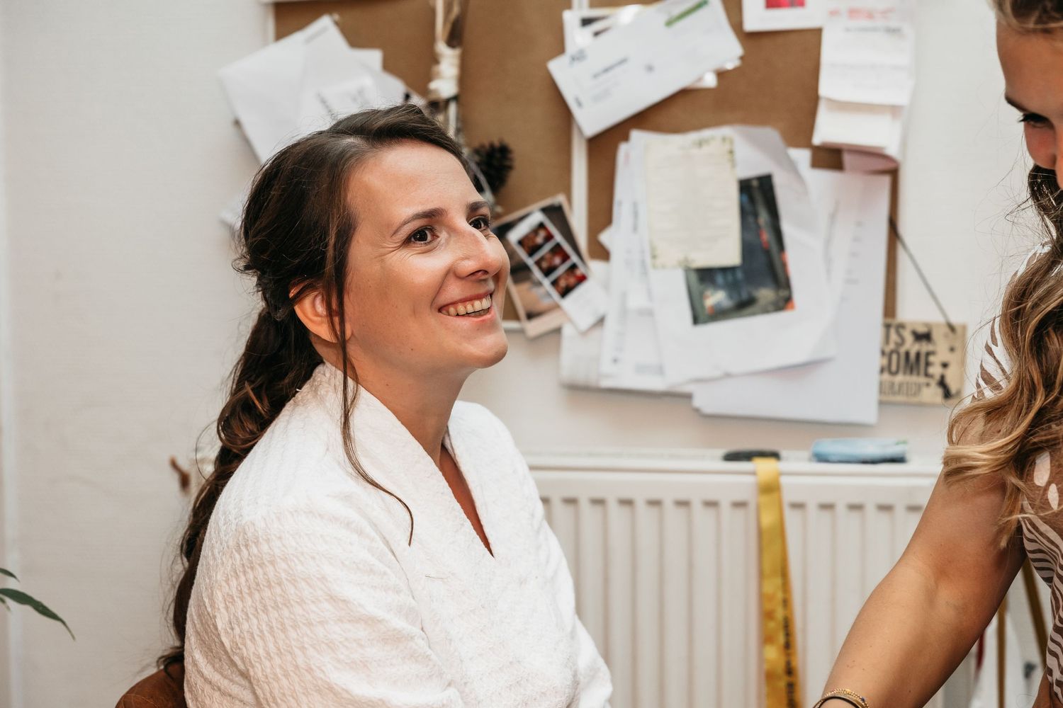 Smiling bride-to-be in white robe during wedding preparation at a beauty salon.