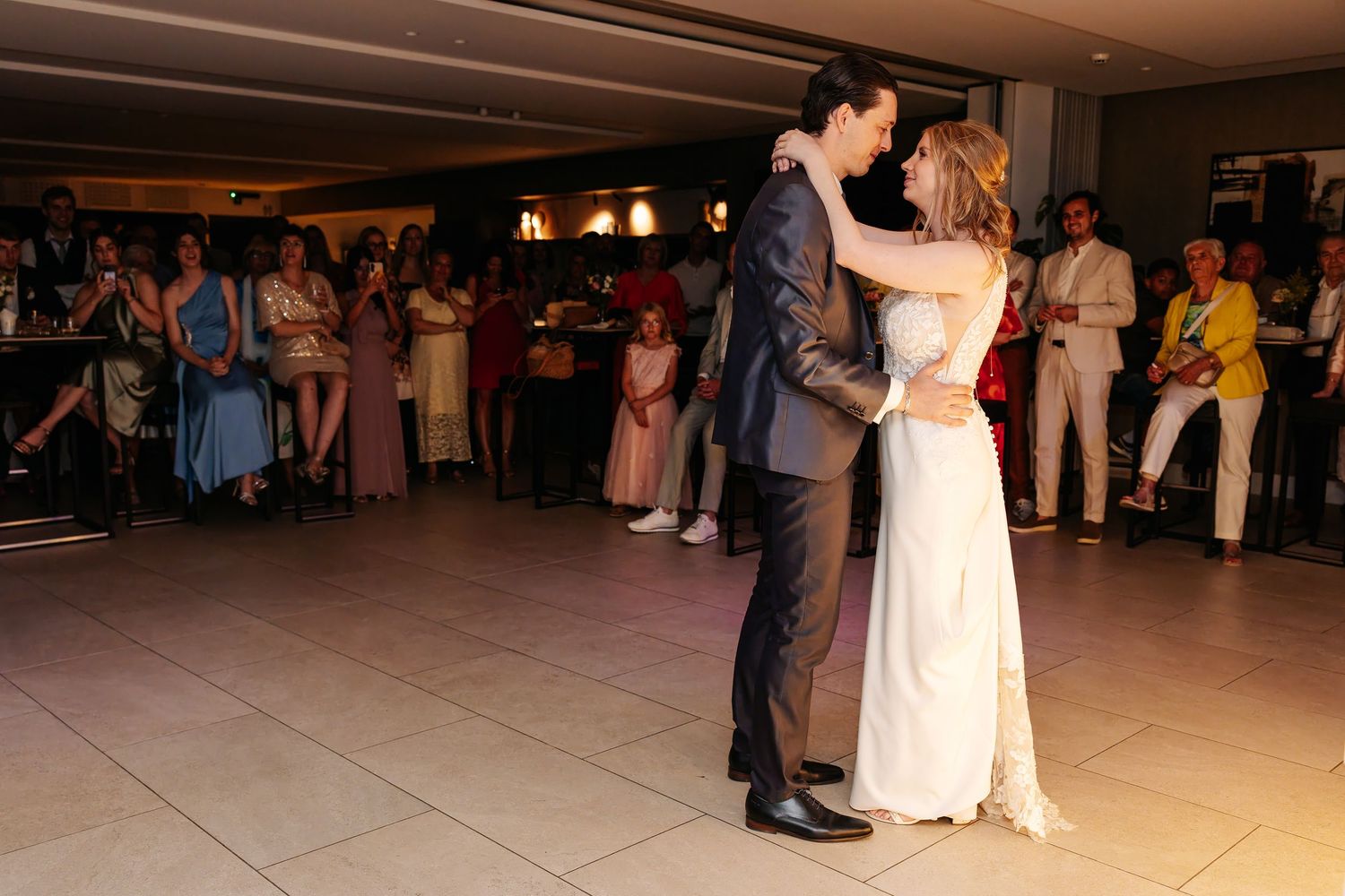 Bride and groom share their first dance at an elegant indoor wedding reception.