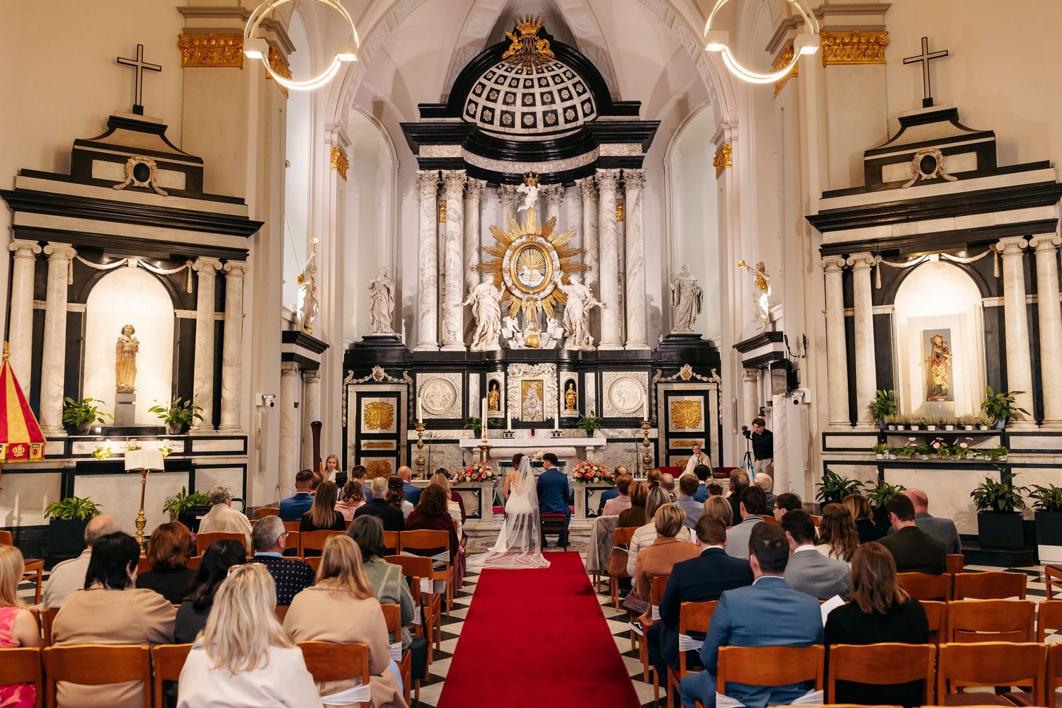 Guests seated in historic church witness couple exchange vows at decorated altar.