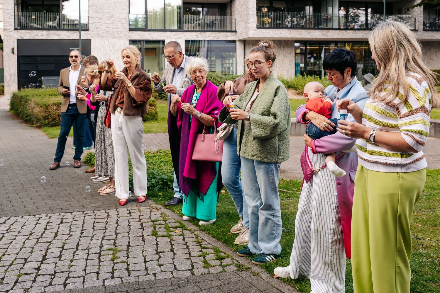 Wedding guests gathered outdoors preparing to blow bubbles for bride and groom celebration.