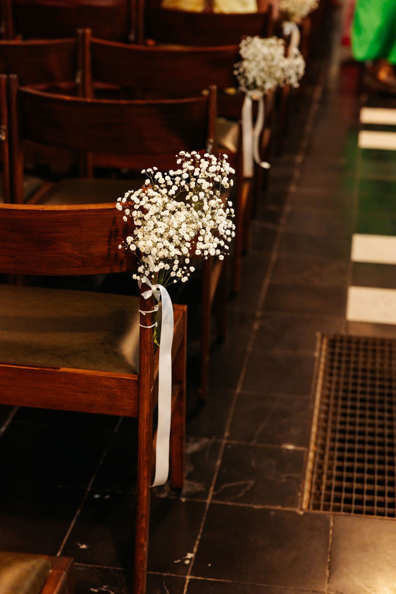 Elegant church aisle chairs decorated with white baby's breath bouquets and white ribbon.