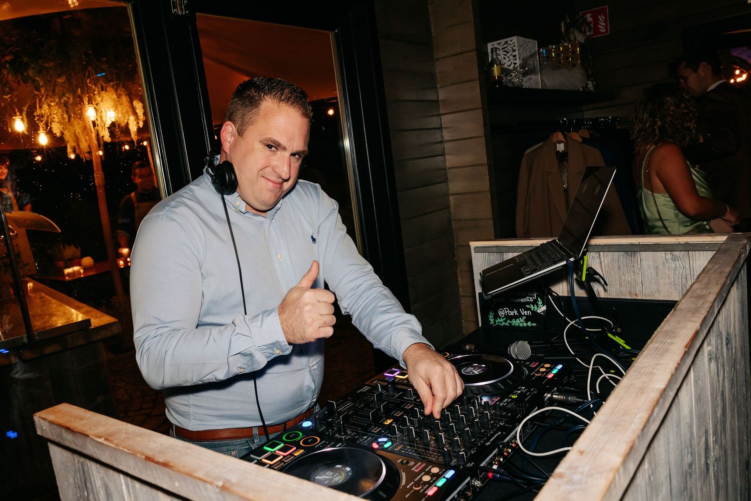 DJ gives thumbs up while mixing music at a wedding reception.