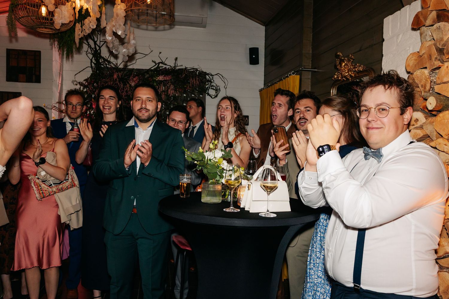 Wedding guests applauding and celebrating at a festive indoor reception venue.