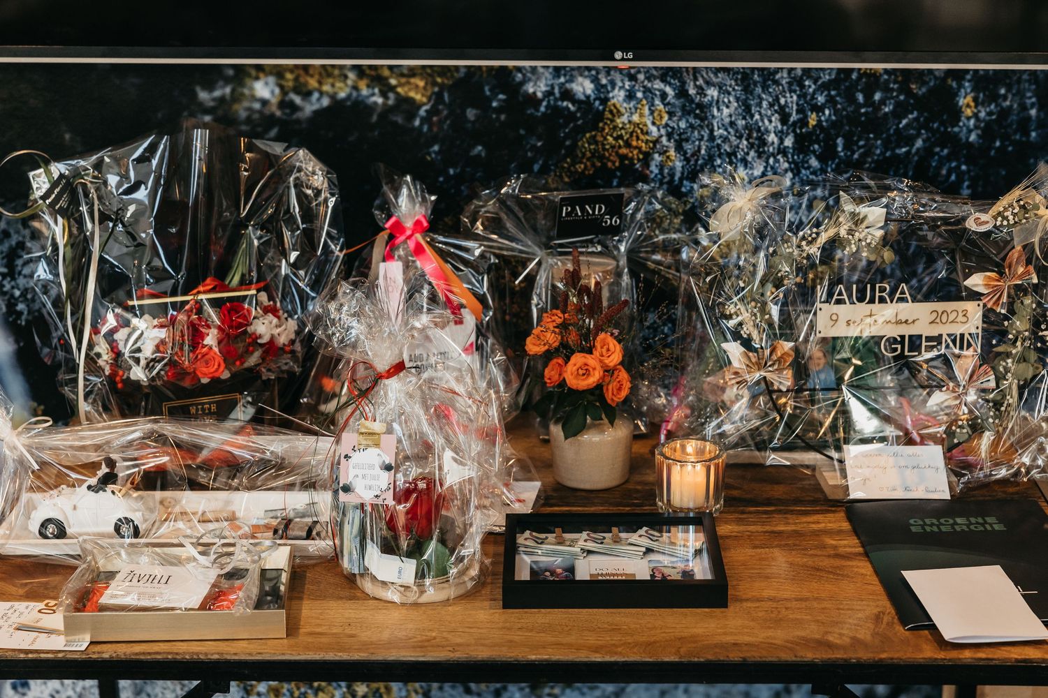Wedding gift table decorated with wrapped floral arrangements, candles, and cards at a reception.