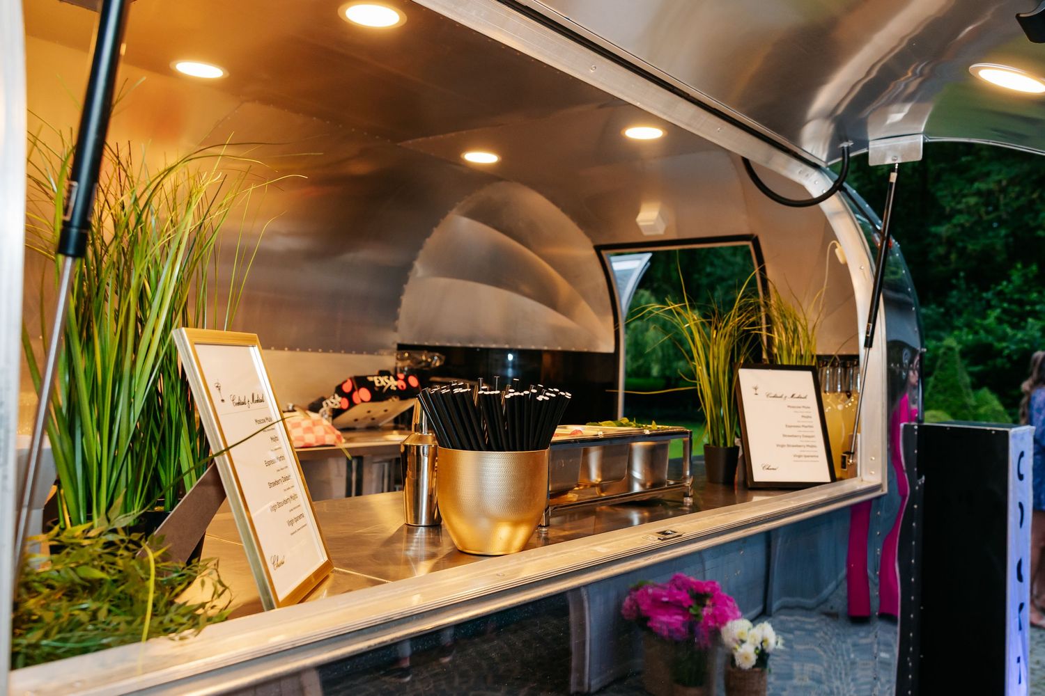 Elegant food service station inside silver airstream trailer catering at evening wedding.